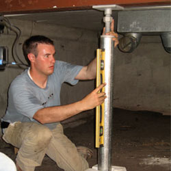 A contractor in Maple Grove installing a crawl space jack post.