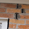 A brick wall displaying stair-step cracks and messy tuckpointing on a Eau Claire home