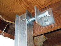 Securing the i-beam system to the top of the floor joist in a foundation wall repair in Menomonie.