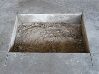 Creating the hole in the garage slab floor during the wall anchor installation in Hibbing.