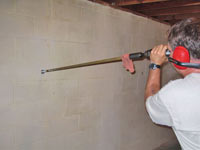 Drilling the hole in the foundation wall for street creep repairs in Hibbing