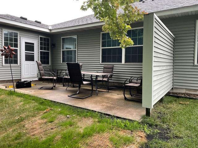 A beautifully leveled and restored backyard concrete patio with patio chairs and table near Blaine, MN after repair.