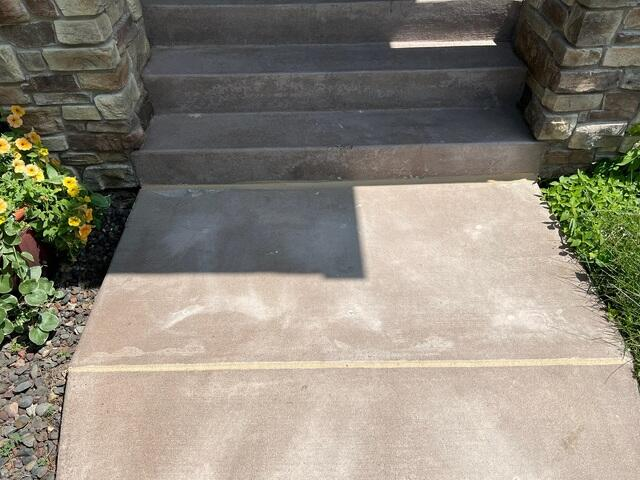 Even and restored concrete sidewalk leading up to home entrance steps in Cumberland, WI after repair.