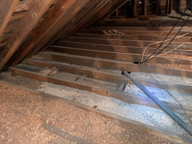 Interior view of an uninsulated residential attic floor showing exposed drywall backing and sparse old material before retrofitting in Medford Wisconsin