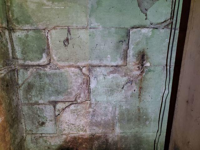 Severe stair-step cracking through concrete foundation blocks with heavy rust and water leaching stains in a Walker, MN basement before repair.