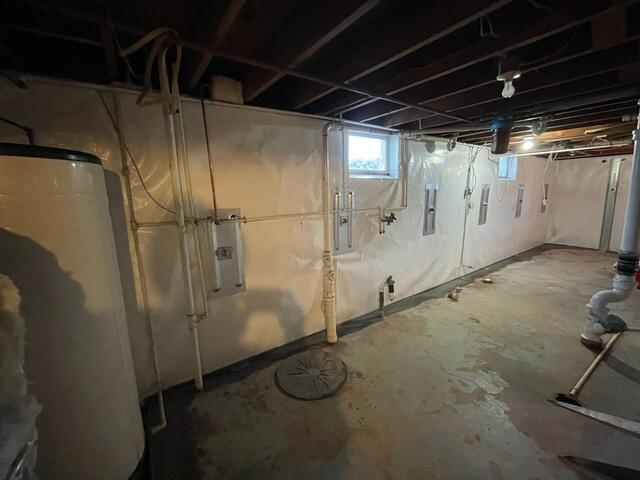 An immaculate basement layout showing bright white CleanSpace encapsulated walls, multiple installed heavy-duty steel GeoLock wall anchor plates, and a sealed sump pump cover in South Range, WI.