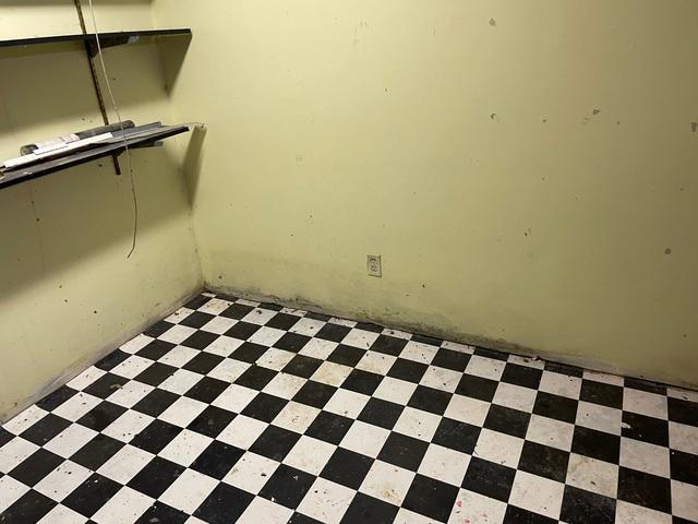 A basement room with a black and white checkered tile floor showing visible moisture staining and dark damp damage along the base of a light yellow wall in Star Prairie, WI.