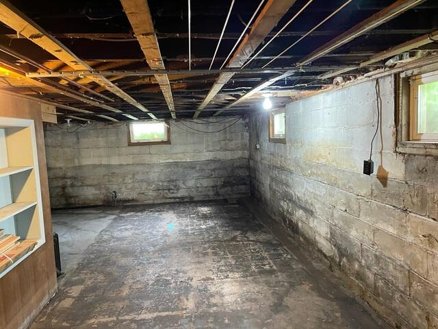 Unfinished and damp concrete block foundation walls before waterproofing in an Ashland, WI basement.