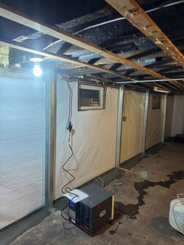 SaniDry basement dehumidifier system operating next to clean white foundation wall liners and steel support columns in Ashland, WI.