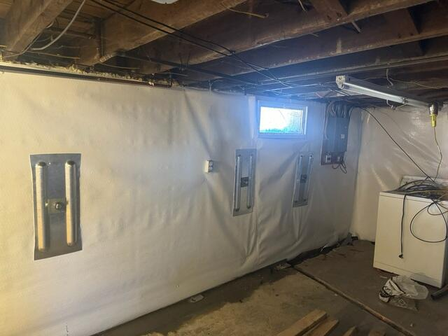 An old room dehumidifier sitting on a stained concrete floor near bare block foundation walls before waterproofing in Barnum, MN.