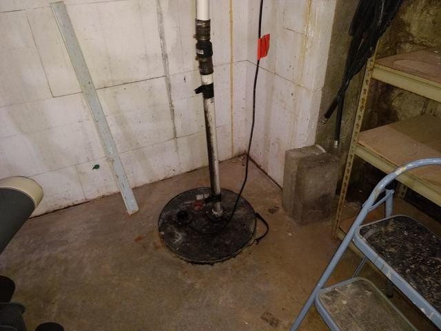 An outdated and unsealed sump pump basin in a concrete basement floor near Chippewa Falls, WI before an upgrade.