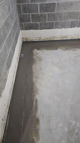 A smooth concrete border sealing a newly completed interior sub-floor perimeter drainage line in a Cohasset, MN basement.