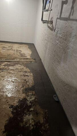 A freshly concreted sub-floor drainage channel perimeter running along a textured foundation wall in Kettle River, MN.