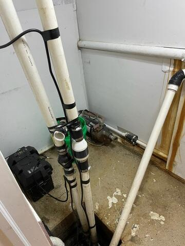 Heavy-duty dual PVC discharge lines with check valves and backup battery wiring installed in a McGregor, MN basement.