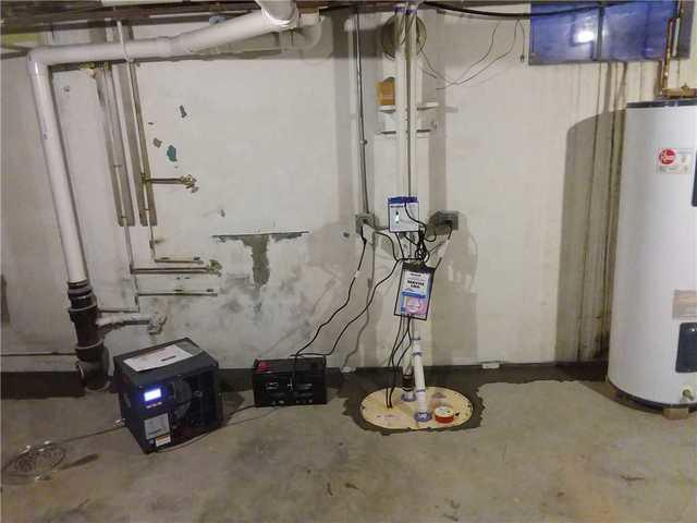 A newly installed heavy-duty sump pump basin with battery backup and a basement dehumidifier on a freshly concreted floor in Medford, WI.
