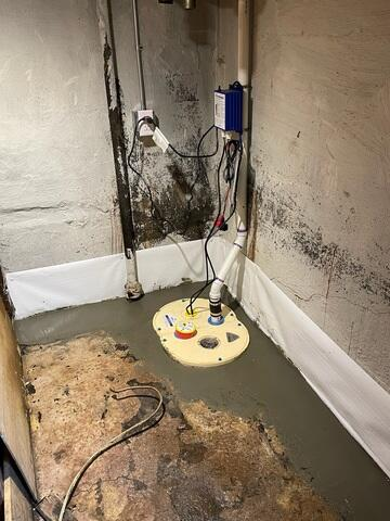 A newly installed DoubleSafe dual sump pump system with clear lids and clean PVC discharge pipes neatly sealed into a fresh concrete floor perimeter in a Superior, WI basement.