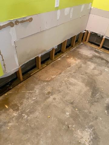 Basement interior under repair with exposed wall studs during a basement waterproofing project in Waconia, MN.