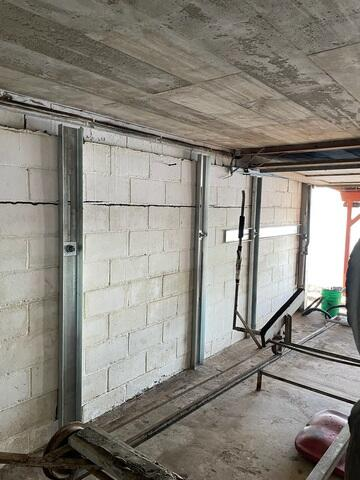 An immaculate basement view inside a boat house featuring newly installed vertical steel foundation wall support channels bolted against a block wall in Amery, WI.