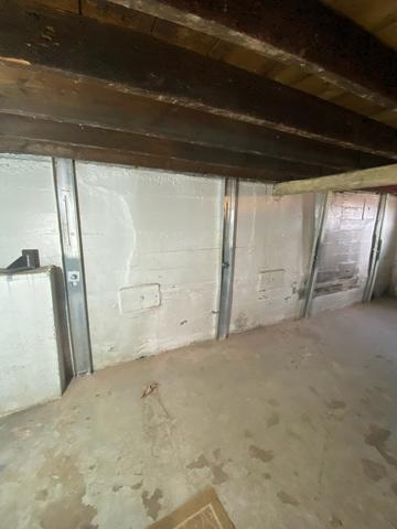 An immaculate completed foundation repair project in Superior, WI showing vertical steel PowerBrace columns and horizontal GeoLock anchor plates reinforcing a white basement wall.