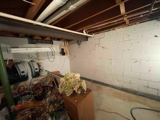 A white-painted concrete block basement wall in Baldwin, WI showing a severe stair-step fracture across mortar joints before structural repair.