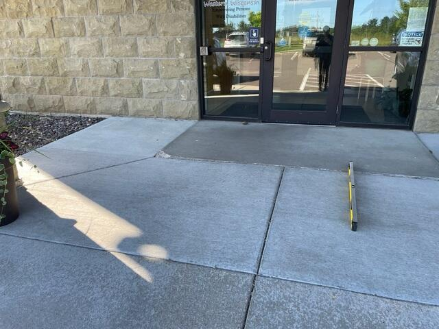 Sunken and uneven commercial concrete entrance walkway showing trip hazard before repair in Menomonie WI