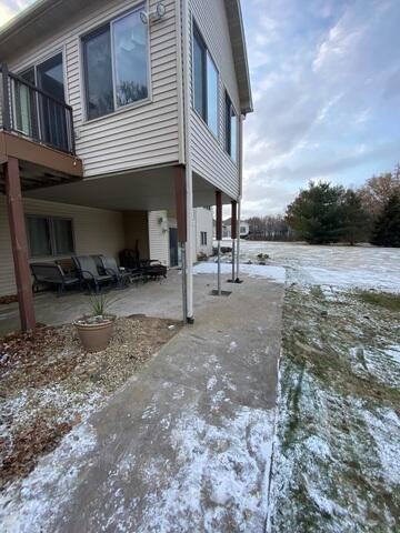 An exterior view of a home addition supported by industrial steel helical piers on a concrete patio during winter with light snow in Andover, MN.