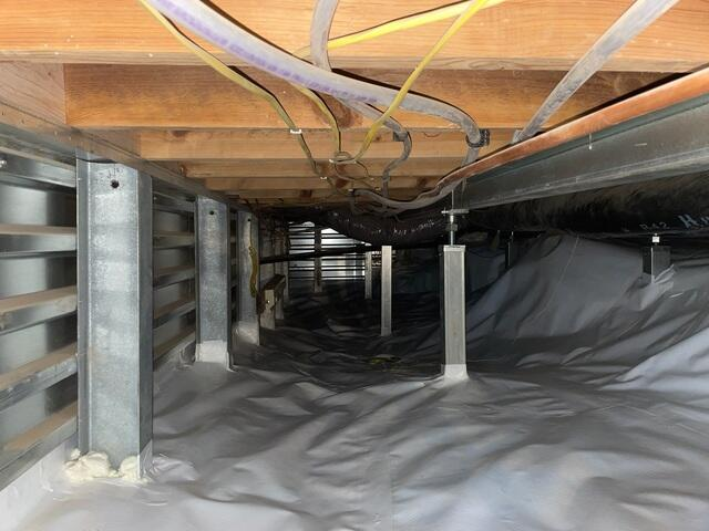 An immaculate view inside an encapsulated crawl space in Danbury, WI featuring a bright white vapor barrier liner and heavy galvanized steel SmartJack support columns.