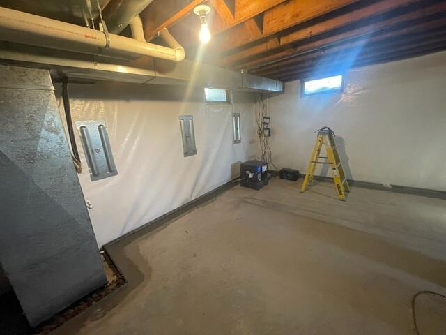 An immaculate basement view in Eau Claire, WI showing three heavy steel GeoLock wall anchor plates cleanly mounted over a white wall liner next to an interior drainage perimeter.