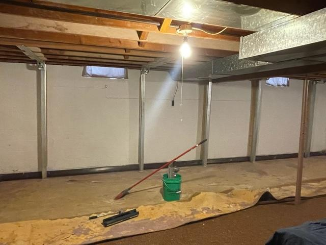 An immaculate view of a completed foundation repair project near Ashland, WI, showing a uniform row of vertical steel PowerBrace support columns cleanly reinforcing a white basement wall.