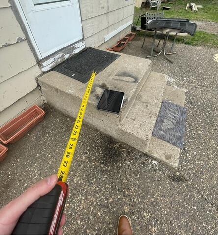 Measuring sunken concrete exterior steps with a tape measure tool before repair in Andover, MN.