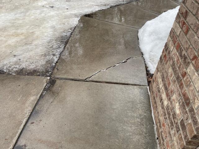 Sinking and cracked concrete walkway experiencing water runoff and snow pooling in Hudson WI before repair