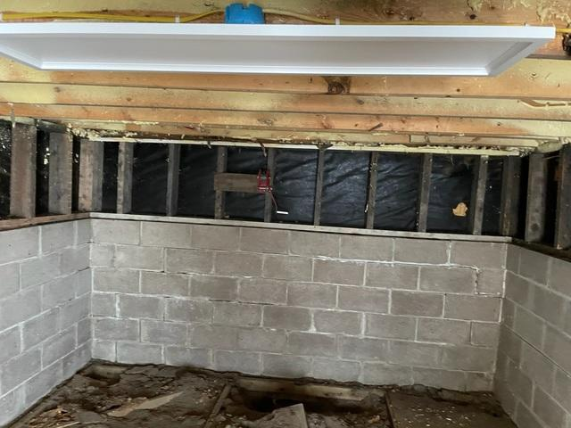 A close-up view of a concrete block basement foundation wall showing a long horizontal crack along the upper mortar joints in McGregor, MN before repair.