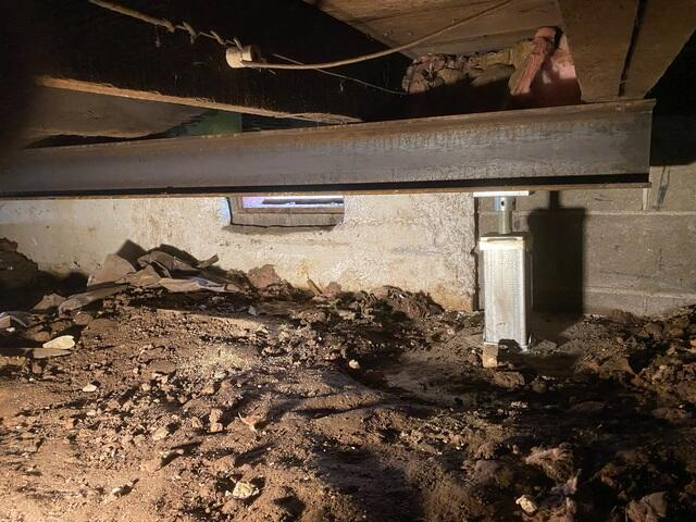 A high-capacity galvanized steel SmartJack adjustable support column mounted beneath a horizontal steel I-beam inside a dirt crawl space in Superior, WI.