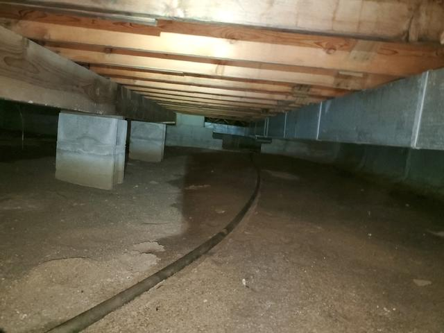 Uninsulated and cold concrete block crawl space walls beneath wood floor framing before repair near Tamarack Minnesota