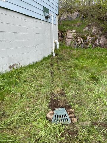 An exterior view of an open cabined crawl space structure on pier supports surrounded by grass in Grand Marais, MN before repair.