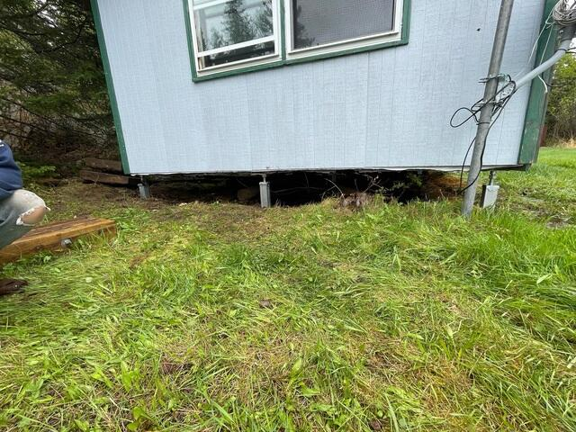 A newly installed heavy-duty SuperSump pump basin with clean PVC discharge lines operational next to a rugged stone foundation wall in Grand Marais, MN.