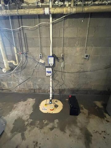 An immaculate view of a newly installed DoubleSafe sump pump system embedded in fresh concrete along a block foundation wall in Wrenshall, MN.
