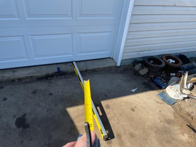 Measuring the significant settlement drop of a sunken concrete garage apron near Hammond WI before repair