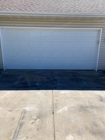 Fully lifted and leveled concrete driveway apron in front of a white garage door near Hammond WI after repair