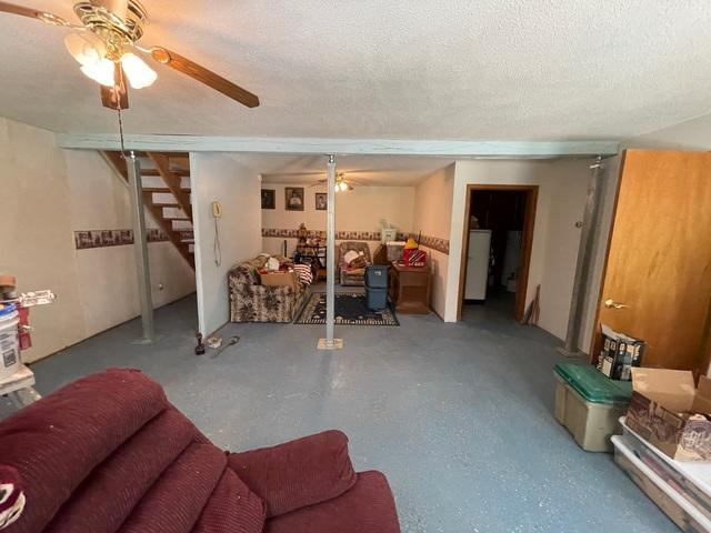 A completed foundation repair project in a basement family room showing three vertical steel adjustable support columns installed beneath a horizontal ceiling beam near a staircase in Trego, WI.