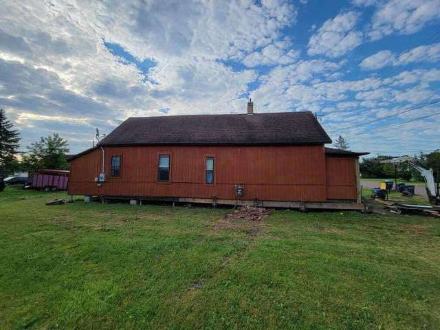 Exterior view of a 150-year-old cabin in Ashland WI receiving foundation repair with helical piers
