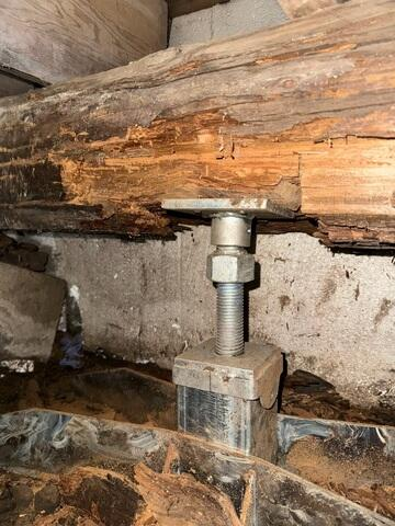 Close-up of a SmartJack steel post supporting a damaged wooden beam in a Stanley WI crawl space