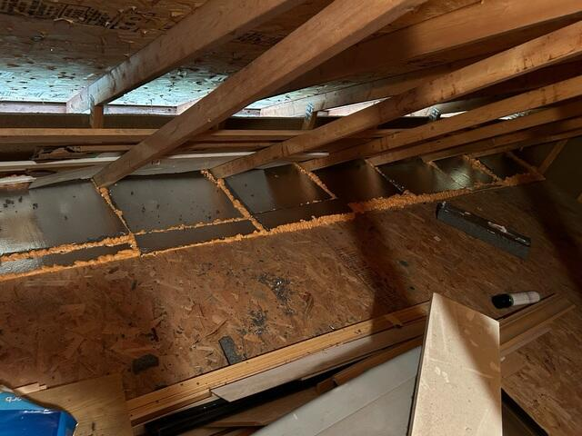 Close up of dark empty attic roof joists and support beams inside a garage structure before repair in Blaine Minnesota