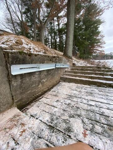 A close-up view of a heavy-duty galvanized steel C-channel waler bar cleanly installed across a concrete retaining wall next to lake-facing steps in Chetek, WI.