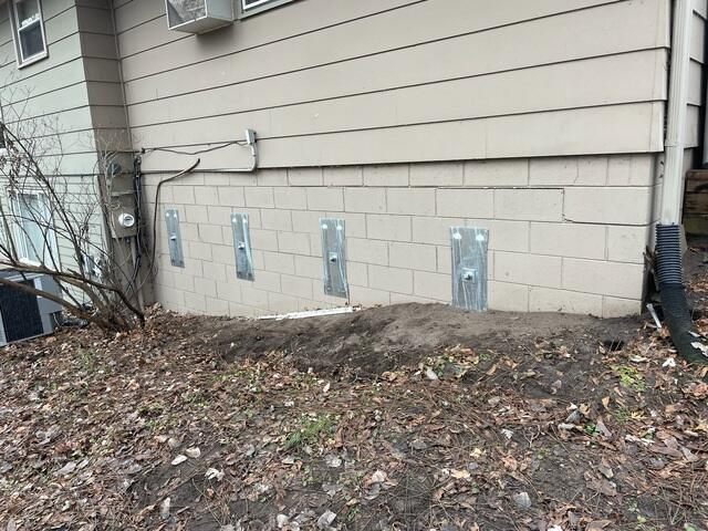 Four heavy-duty galvanized steel GeoLock wall anchor plates vertically bolted along an exterior concrete block foundation wall in Fridley, MN.