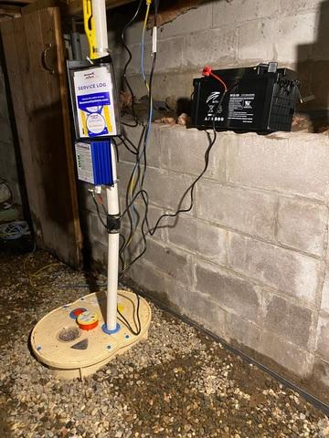 Heavy duty sump pump system installed in a half basement floor next to a concrete block wall with an UltraSump battery backup near Spooner Wisconsin