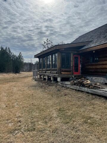 A large rustic log cabin home in Holyoke, MN showing an unlevel three-season room extension supported by concrete columns before foundation stabilization.