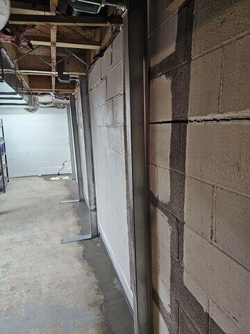 A long view inside a basement in Grand Marais, MN showing a series of vertical steel PowerBrace support columns cleanly installed to stabilize a cracked block wall.