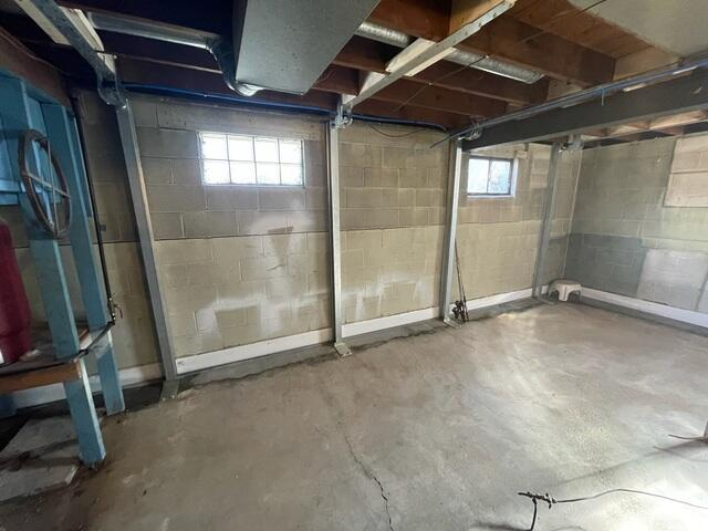 A close-up view of three high-tensile steel PowerBrace I-beams mounted vertically against a cracked block wall and anchored to a concrete floor in Esko, MN.