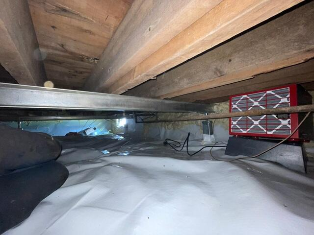 An immaculate crawl space encapsulation project in Ashland, WI featuring a bright white vapor barrier liner, a vertical steel support jack, and a red Sedona dehumidifier operating cleanly on a low-profile base.